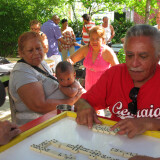 Jorge Torres and family and friends playing dominoes in the garden where he grows cane.