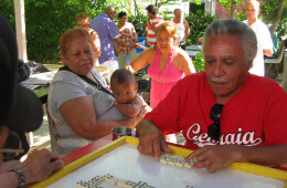 Jorge Torres and family and friends playing dominoes in the garden where he grows cane.